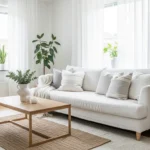 "Bright modern white living room with white sofa, layered rugs, wooden accents, and indoor plants for a clean and cozy look."