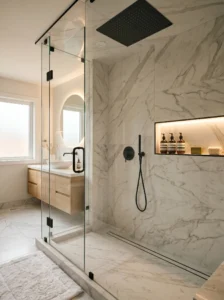 Modern walk-in shower with frameless glass, rainfall showerhead, and large marble-look tiles.