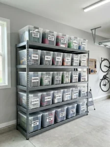 Clear labeled plastic storage bins stacked neatly on garage shelves.
