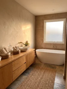 Bathroom featuring warm beige and clay tones with natural wood and stone finishes.