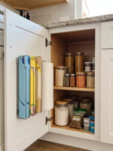 Cabinet door organizer storing foil, plastic wrap, and parchment paper
