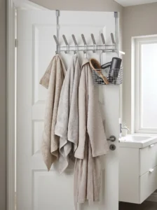 Over-the-door bathroom rack with metal hooks holding towels and a robe alongside a basket for hair tools.