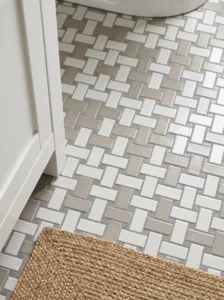 White and warm-gray square mosaic tiles arranged in an alternating basketweave pattern on a bathroom floor.