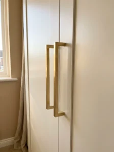 Brushed brass handles on IKEA PAX wardrobe doors adding a refined, high-end finish to simple cabinetry.