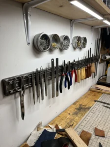 Wall-mounted magnetic strips organizing metal scissors, tweezers, rulers, and small craft tools above a worktable.