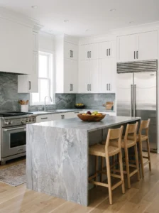 Cool gray quartzite kitchen countertop with silvery natural veining, white cabinets, and stainless steel appliances.
