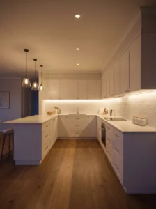 U-shaped kitchen with warm under-cabinet LED lighting, recessed ceiling lights, and bright, usable countertops.