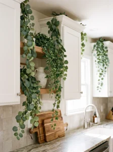 Trailing faux greenery draped naturally above white kitchen cabinets