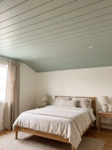 Pale sage-green painted shiplap ceiling adding subtle texture to a calm neutral guest bedroom.
