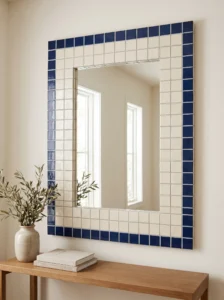 Rectangular mirror framed with a double border of deep navy square mosaic tiles around a light neutral center.