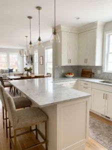 U-shaped kitchen with a spacious peninsula breakfast bar, quartz countertop, pendant lights, and comfortable bar stools.